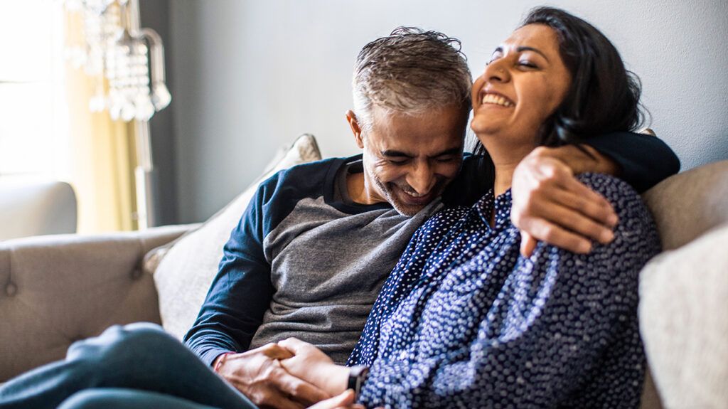 Couple on couch embracing and smiling