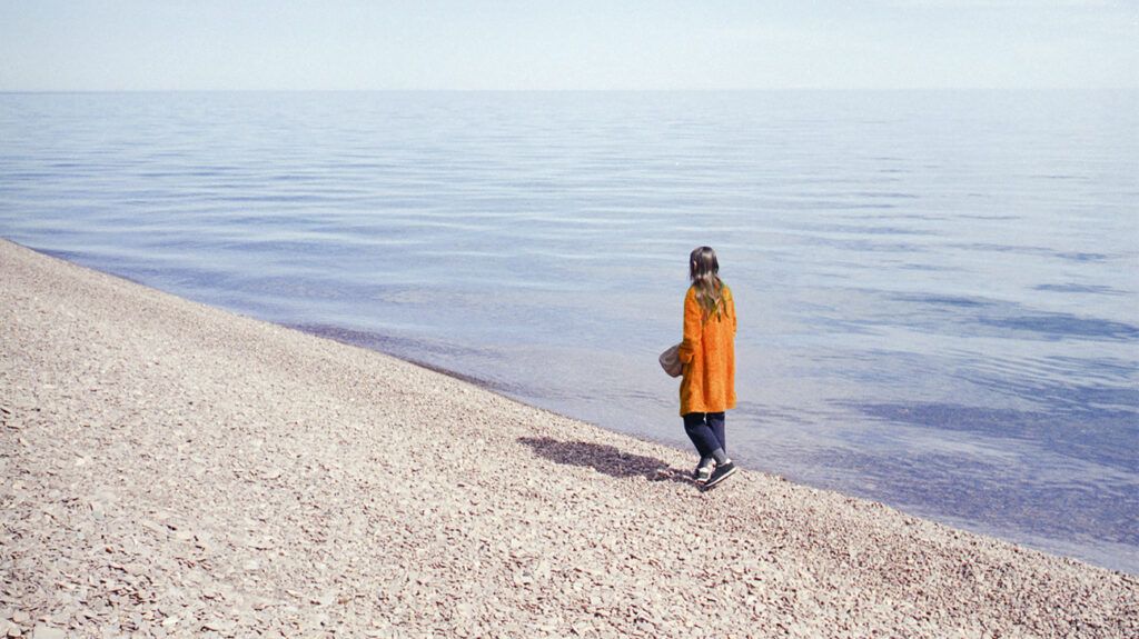 Woman walking by edge of a rocky shoreline