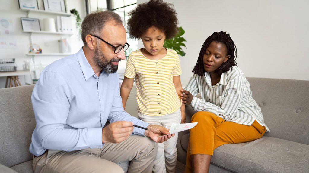 Male therapist talking to a child and mother