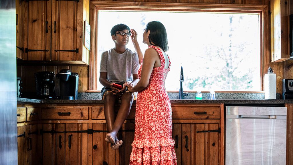 mother comforting son in kitchen