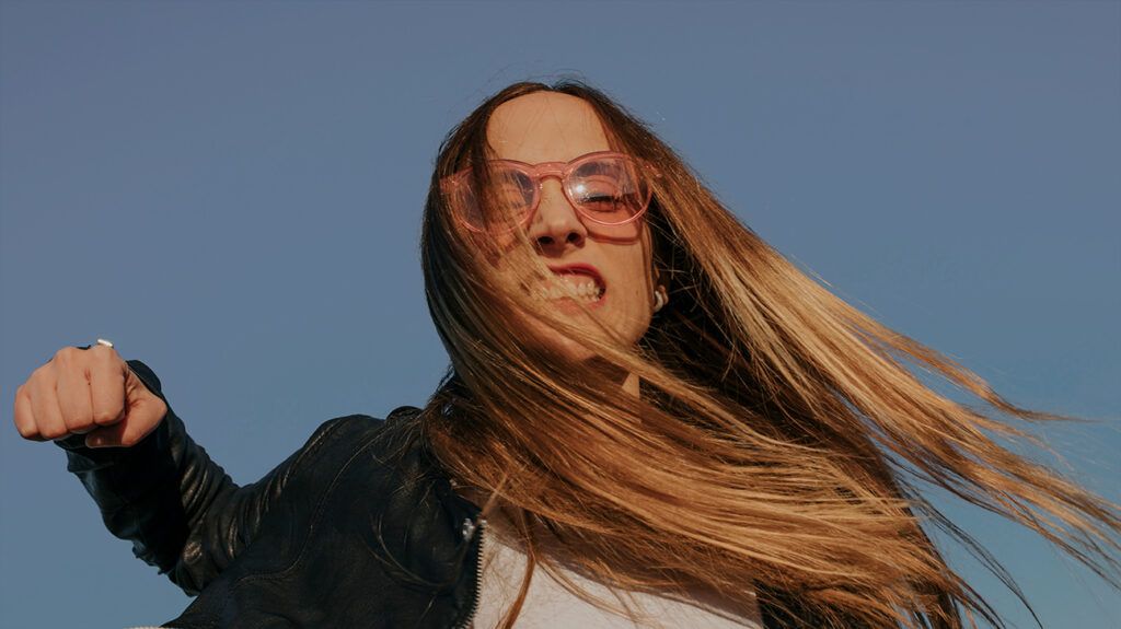 Grimacing woman aggressively punching sky