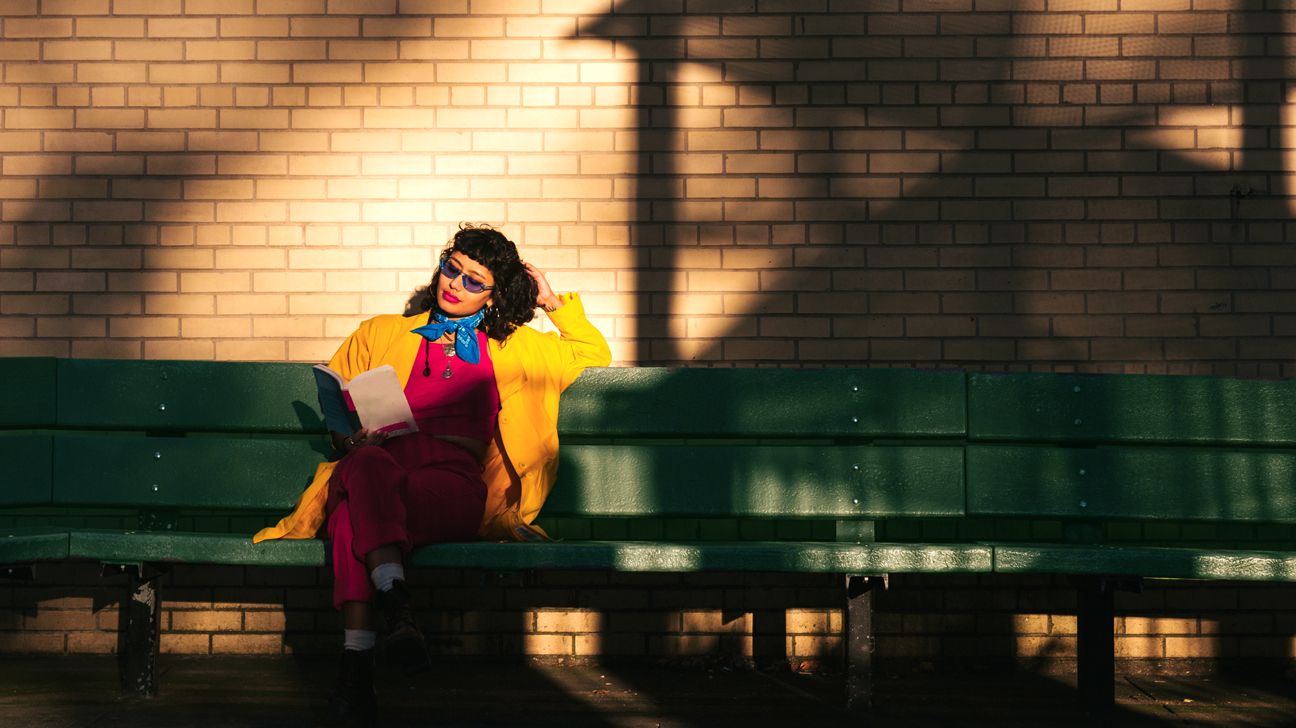 person sitting on a bench reading a book