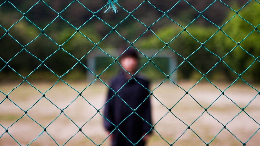 woman blur standing behind fence net